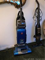 Photo showing the blue Hoover WindTunnel upright vacuum in good condition with visible clear dust bin and base.