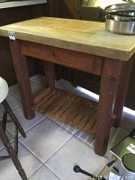 Full view of the wooden butcher block table showing the thick block top, single drawer and lower rack.