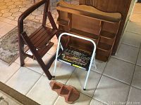 Wooden and metal step stools with wooden wall shelves arranged on tiled floor.