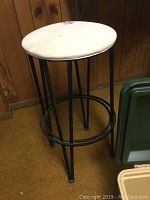 Single bar stool showing white round cushioned seat and black metal base
