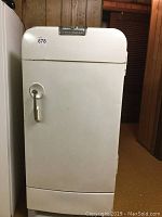 Front view of vintage white Frigidaire refrigerator showing door and chrome handle.