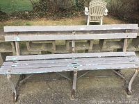 Full view of one park bench with wooden slats and iron legs, showing wear and rust
