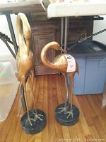 Two brass bird sculptures side by side, full height view
