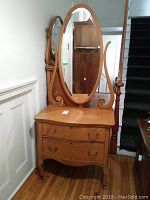 Full view of antique solid wood vanity with attached oval mirror and harp supports, showing overall condition and style.