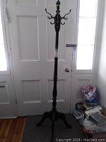 Full height view of the wooden coat tree standing against a door