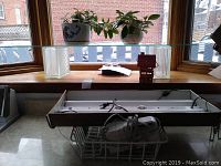 Wide shot showing the fluorescent grow light, two potted plants on a large glass shelf, two glass blocks, and a red Laura Secord votive holder.
