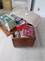 Cedar chest open showing collection of linens inside including folded fabrics and packaged bedspread set