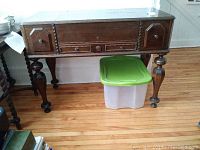 Front view of closed desk showing two outer drawers, central drawer and turned legs
