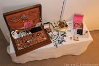 Wide view showing all jewelry items arranged on a table including wooden box and travel box, necklaces, bracelets, pins, cuff links, and earrings.