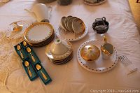 Photo showing the full coffee set including coffee pot, plates, cups, saucers, cream and sugar set, and Birks spoons in their boxes on a table with a lace cloth.