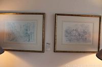 Photo showing two framed prints on a wall, one depicting an English street scene, the other a countryside house by water, each 10 by 14 inches.