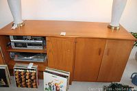 Front view of the media cabinet showing the top surface, closed doors, and vinyl records placed in front.