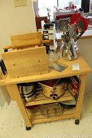 Photo of the kitchen cart top surface showing the knife block with knives, a rolling pin, Good Grips box grater, and jar with utensils.