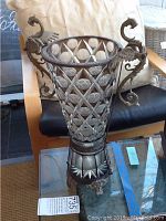 Front view of the tall glass vase with metal dragon handles and metal base.