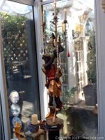 Full view of painted blackamoor figure holding six-light candelabra beside window