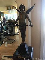 Full front view of the winged statue on marble slab