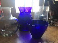 Four glass vases on wooden floor, two blue glass and two clear glass including bubble vase