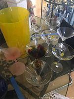 Photo showing large yellow vase and assorted stemware including clear martini glasses and wine glasses with decorative dots and colored stems.