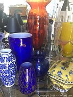 Overall view of the lot showing the various vases and the porcelain box arranged together on a glass surface.