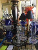 Photo showing the variety of candle holders including clear and cobalt blue glass with decorative elements and different heights.