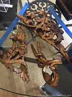 Carved wood decorative pieces with leaf and scroll designs on a glass table.