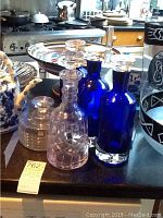 Full set of 3 clear and 3 blue glass decanters displayed on a table with kitchen background.