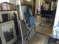 Three paintings on floor and leaning against wall in room, showing the lot contents.