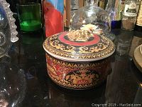 Side view of closed trinket bowl showing baroque pattern and gold Medusa relief on lid