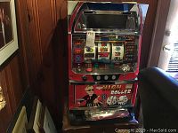 Front angle view of full slot machine on wooden surface, showing cabinet graphics and coin tray