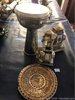Photo of African drum, two elephant figurines, and painted plate on a black surface
