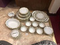 Photo showing the full set with stacked plates, teacups, and serving pieces arranged on floor.