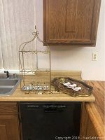 Gold metal and glass display shelf, trays and porcelain hands on kitchen counter