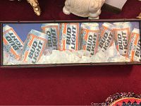 Full view of the Budweiser Light advertising lighted sign featuring multiple cans surrounded by ice placed on red carpet.