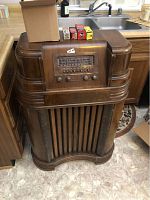 Front view of floor-standing wooden console radio on kitchen floor
