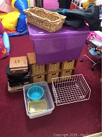 Lot showing large purple storage tote and wooden rack with six wicker baskets beneath