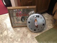 Coors beer mirror and Coors Light bottle wall clock placed on floor showing front views.