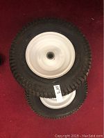 Pair of tractor tires stacked, showing tread and white metal wheels.