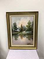 The framed acrylic painting showing a scenic landscape including a house, trees, and water reflection.