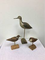 Photo showing the three bird decoys: Willet, Killdeer, and Sanderling, displayed on a white surface against a plain wall.