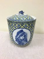 Front view of jar showing yellow and blue patterned design with oval portrait of a girl in bonnet.
