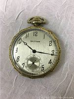 Front view of Waltham pocket watch with white dial, black Arabic numerals, and smaller seconds subdial, showing black hands and winding crown.