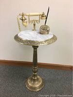 Full view of the vintage style rotary telephone stand with marble top and brass base, including the rotary telephone handset and pen holder with pen on top.