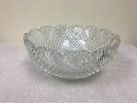 Side view of the clear cut crystal leaded glass bowl showing the shell motifs on the scalloped rim and detailed cut patterns.