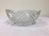 Side view of the antique cut crystal leaded glass bowl showing detailed cut patterns and the scalloped rim with no visible cracks but flea bite chips.