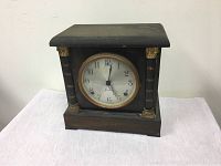 Front view of the Sessions pillar mantle clock showing black wooden case with decorative pillars and a round dial with aged white face and black numbers.
