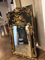 Front view of entire mirror leaning against wall on hardwood floor