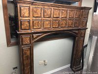 Front view of entire elm wood fireplace mantel surround showing raised-panel design and central arched opening