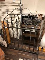 Front view of metal fence gate used as fire screen showing decorative fleur-de-lis and scrollwork design at top