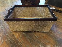 Image showing exterior view of rectangular wicker basket with dark wood edges and integrated handles on sides.