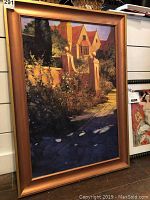 Frontal photo of framed giclee reproduction showing cottage and garden with shadowed walkway in gold painted wooden frame without glass.